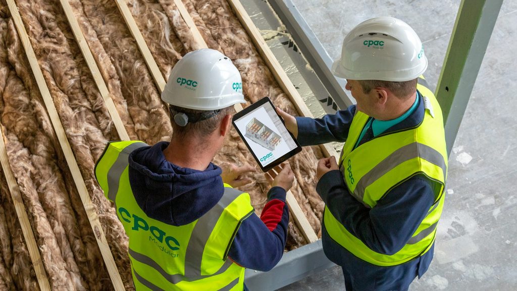 Twee vakmensen bekijken op een tablet de isolatie van een dakconstructie met minerale wol tussen houten balken